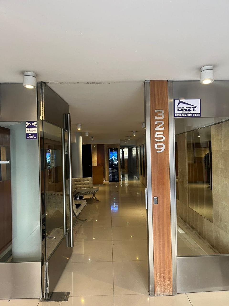 Hall de ingreso de un edificio de CABA con cartel de DNZT, lector de acceso y tótem al fondo del pasillo